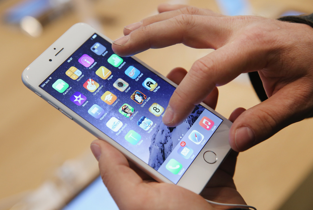 BERLIN, GERMANY - SEPTEMBER 19: A shopper ltries out the new Apple iPhone 6 at the Apple Store on the first day of sales of the new phone in Germany on September 19, 2014 in Berlin, Germany. Hundreds of people had waited in a line that went around the block through the night in order to be among the first people to buy the new smartphone, which comes in two versions: the Apple iPhone 6 and the somewhat larger Apple iPhone 6 Plus. (Photo by Sean Gallup/Getty Images)